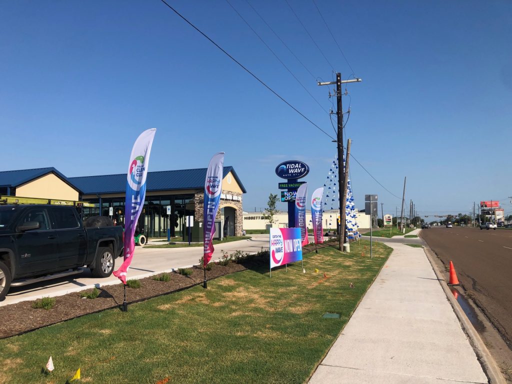 outdoor advertising materials of flags, banner and banner frame, and pennant lines being used to market a new a car wash